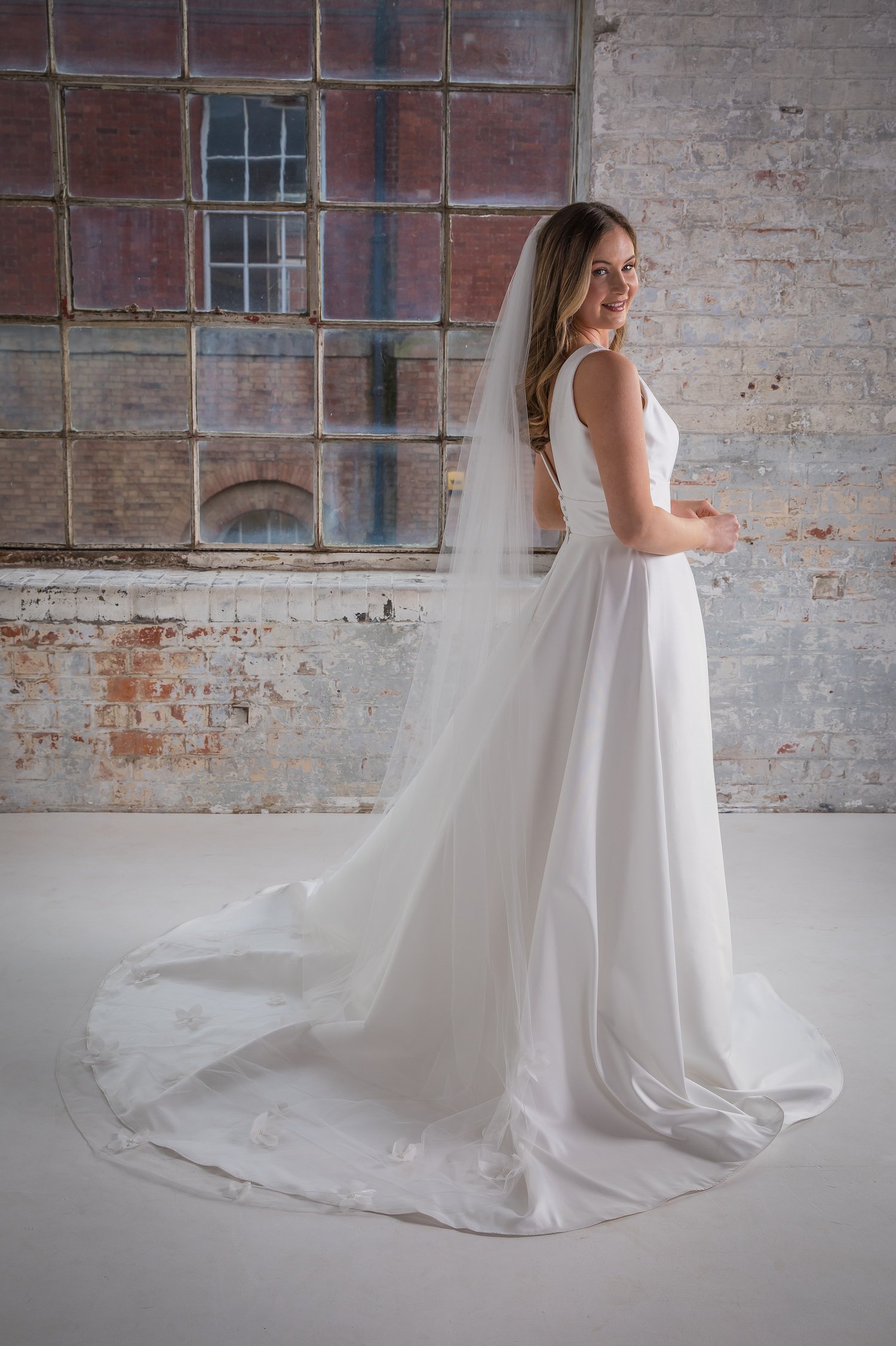 Bride showing the fitted back of her wedding dress and veil